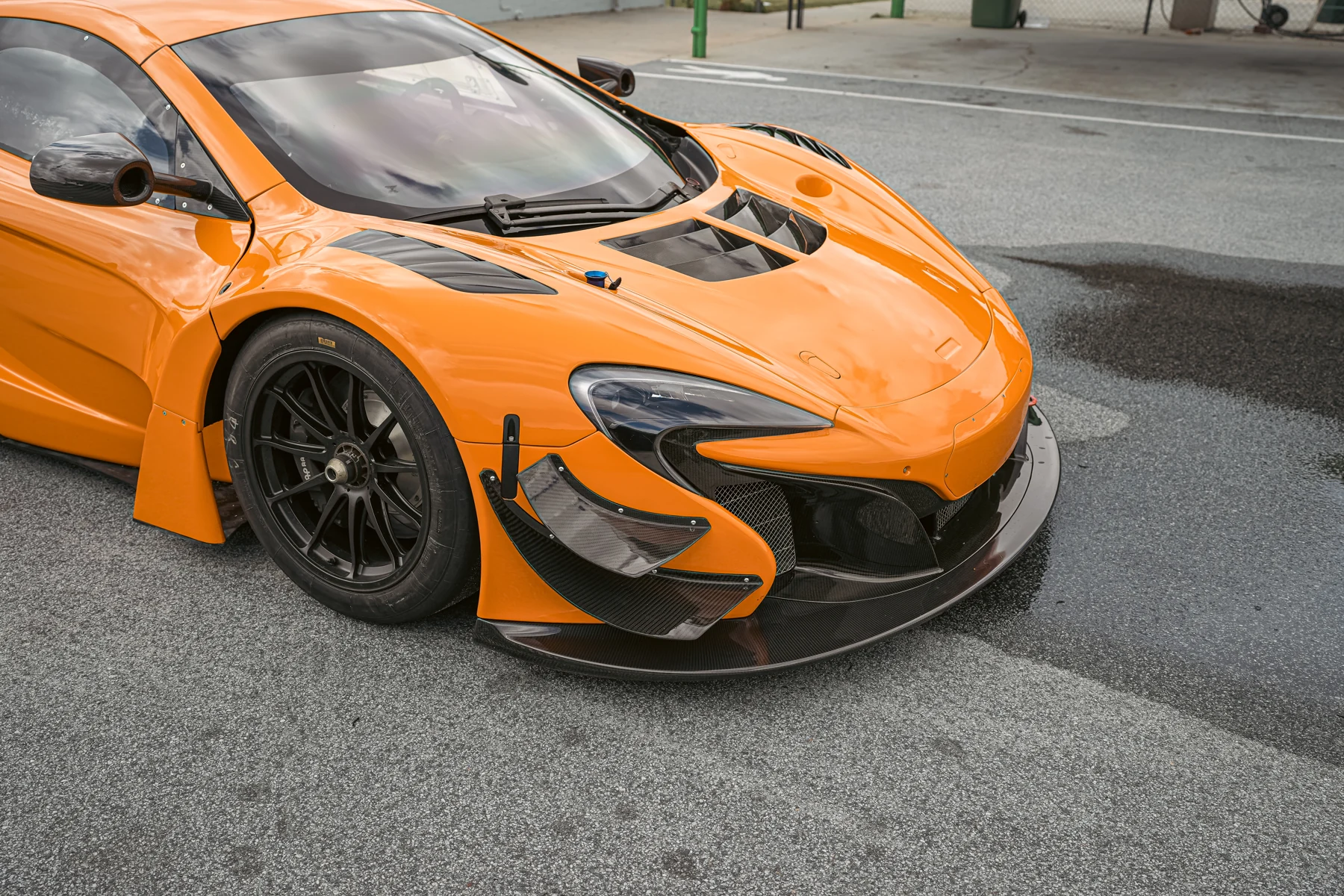 Photographic detail of the McLaren's front wheel, splitter and orange bodywork